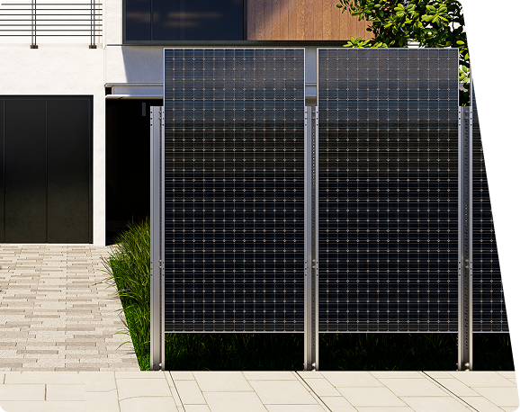 Two large, upright solar panels with metal frames stand before a modern building with a dark garage door and a paved path.