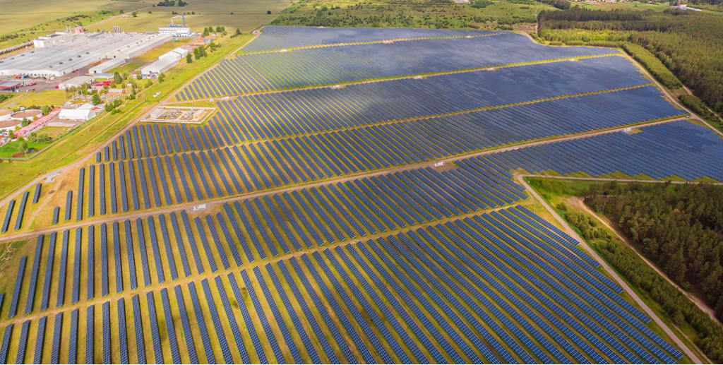 Aerial view of a vast utility-scale ground mount solar power array featuring fixed tilt solar panels.