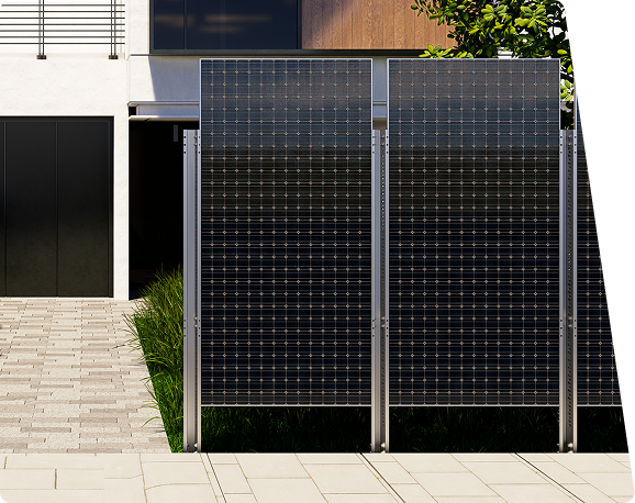 Two large, upright solar panels with metal frames stand before a modern building with a dark garage door and a paved path.